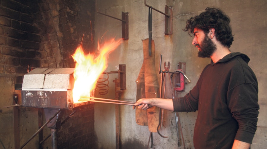 Jon at work on the forge under the arches of Peckham Rye Station.
INSET; knives made by Blenheim Forge