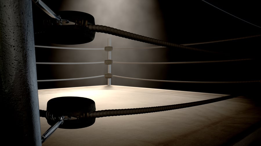 A closeup of the corner of an old vintage boxing ring surrounded by ropes spotlit by a spotlight on an isolated dark background