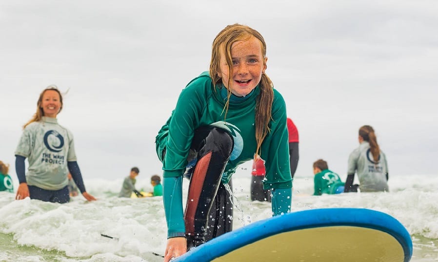 A girl learns to surf with help from a Wave Project coach