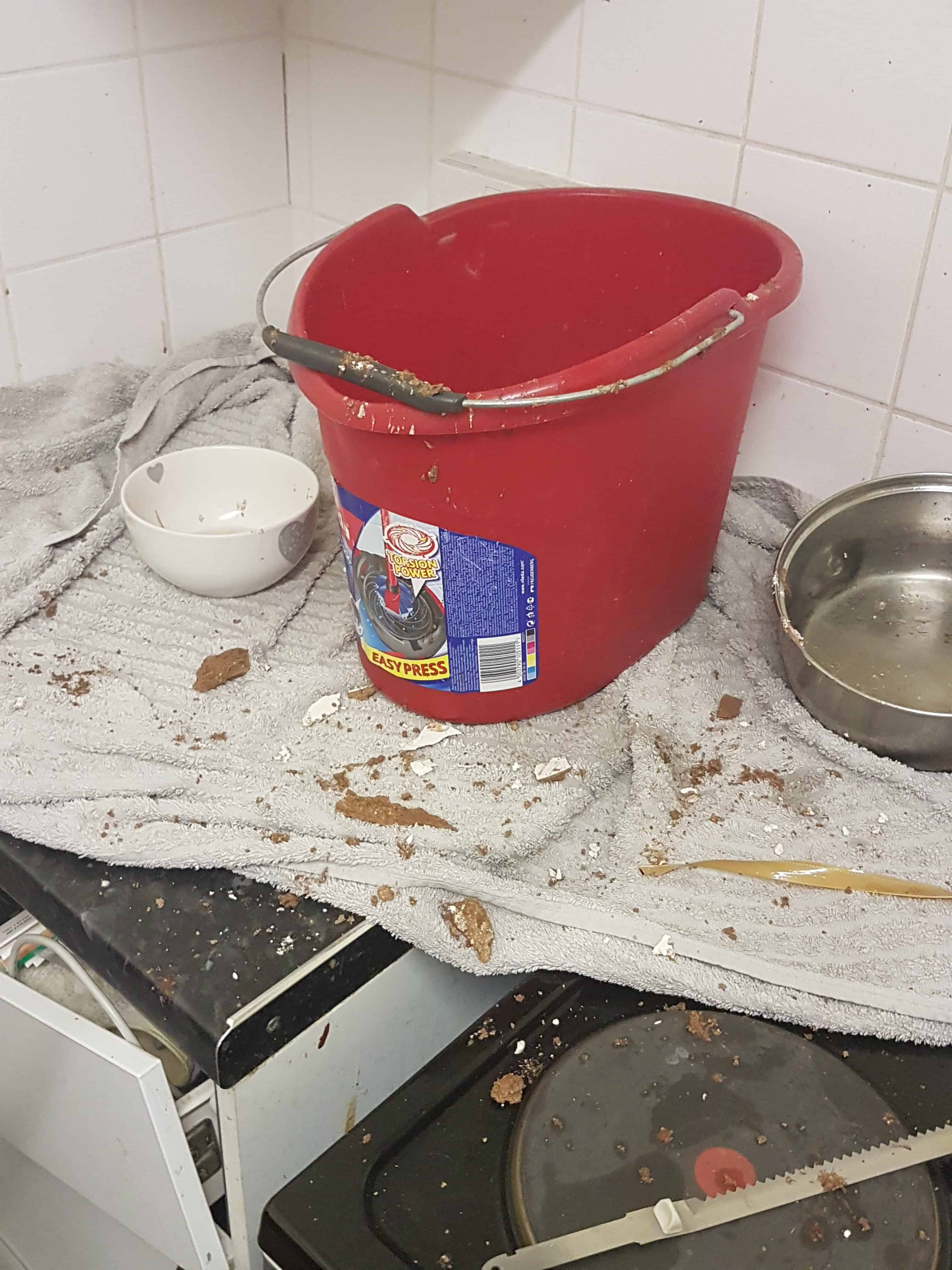 A bucket catching water, and bits of the ceiling, in the Tissington Court flat