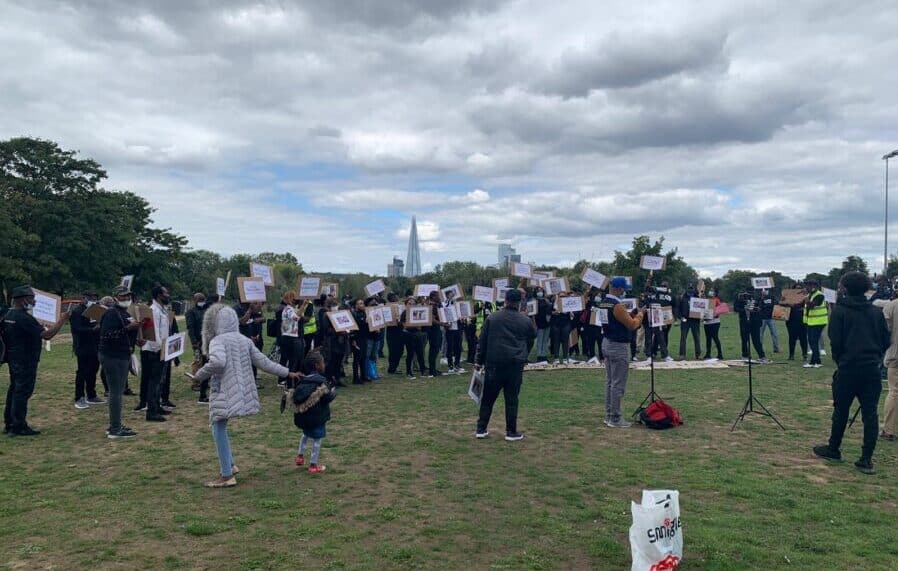 A coalition of groups hold placards in Burgess Park during the protest on August 31