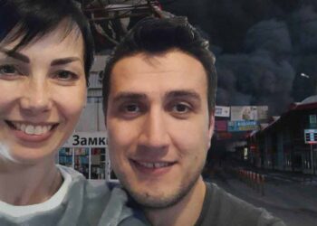 Kamil Salmanov and his partner Natalia Lepekha, in front of backdrop of the hometown they fled