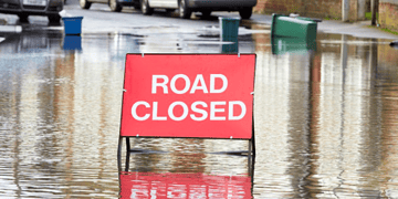 A stock image of a road closure sign in a flood road