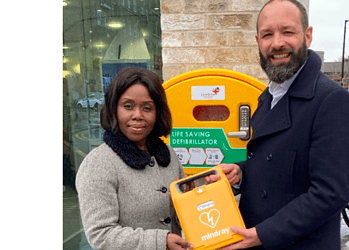 Cllr Evelyn Akoto (left) and Council Leader Kieron Williams (right) presenting one of the new defibrillators