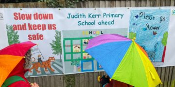 Children have unveiled a road safety banner after a car crashed through their school’s fence
